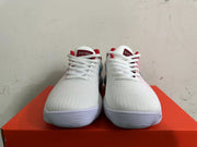Front view of white Nike low-top sneakers with white laces and red tongue details.