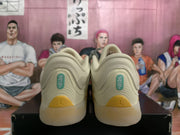 Rear view of the beige Jordan sneakers showing padded collars, teal heel details, and yellow outsole accents.