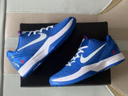 Overhead product view of the blue and white sneakers arranged on a black shoebox.