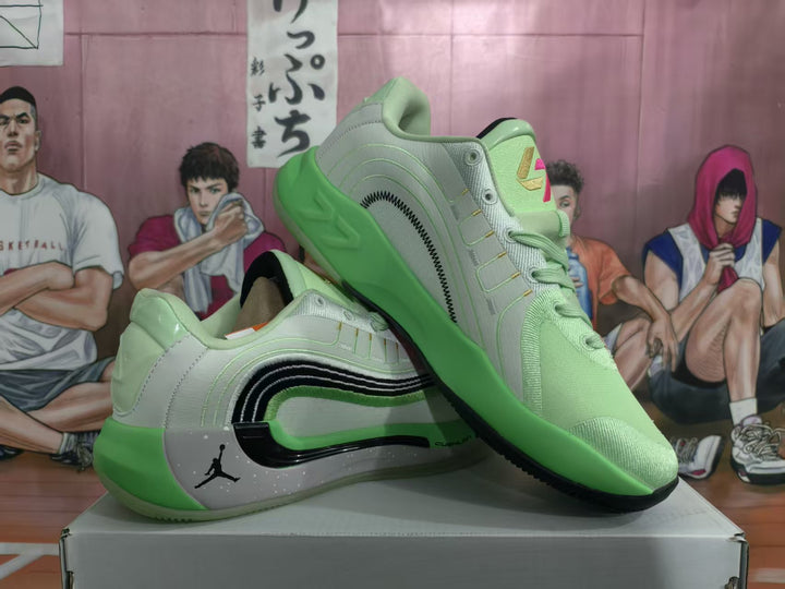 Pair of mint green and light gray Jordan basketball sneakers displayed on a shoebox, showing the side detailing and green outsole.