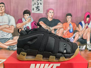 Side profile of a black Nike sneaker showing layered panels, textured upper sections, visible cushioning, and a gum-colored outsole.