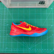 Side view of a red Nike basketball sneaker with yellow Swoosh branding, yellow laces, blue lining, and blue outsole on a green cutting mat.
