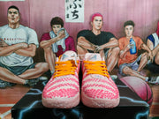 Front view of pink and pale Nike basketball-style sneakers with bright orange laces and textured pink detailing.
