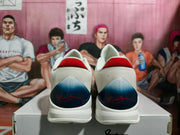 Rear view of the sneakers showing white woven collars, navy heel panels, and red graphic details.