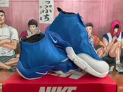 Angled view of blue and white Nike The Glove sneakers showing the covered high-top upper, white toe sections, and contrasting outsole.