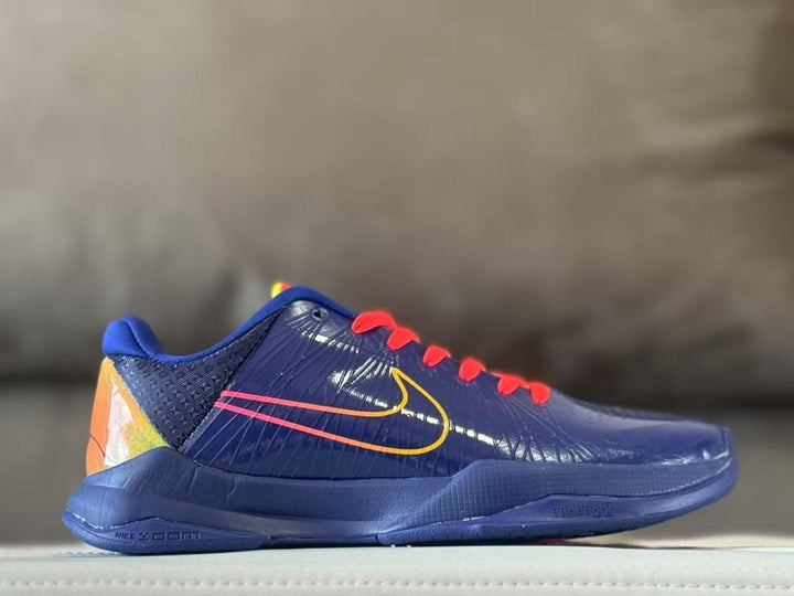 Side profile of navy Nike Kobe 5 sneakers with red laces, yellow-gold branding, and an orange-yellow heel panel.