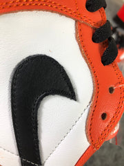 Close-up of the black side logo, white panel and orange stitched overlay.