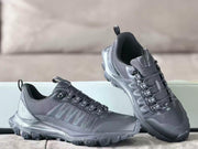 Angled view of two black Alo sneakers showing the padded collars, pull tabs, layered uppers, and lugged soles.