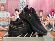 Angled view of paired black Nike Book 1 sneakers showing the Swoosh details, tan-gold trim, laces, and hangtag.