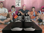 Front view of black basketball shoes with white laces and white Kobe-style symbols on the tongues