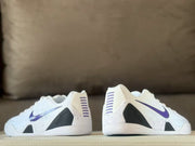 Rear and side view of the white Nike Kobe 9 sneakers showing purple heel striping, black panels and speckled detailing.
