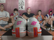 Rear view of white Nike basketball shoes showing pink heel logos and orange heel details.