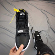 Front view of the black high-top sneaker with perforated toe panel, laces, and forefoot strap.