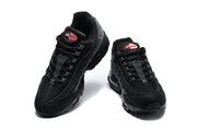 Front view of a pair of black Nike Air Max 95 sneakers with grey layered panels and red logo details.