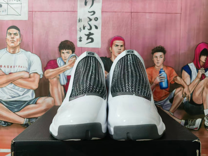 Pair of white and gray high-top basketball sneakers viewed from the front, showing black textured-look panels and dark toe accents.