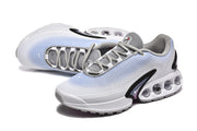 Angled view of white and light blue Nike Air Max DN sneakers with gray laces.