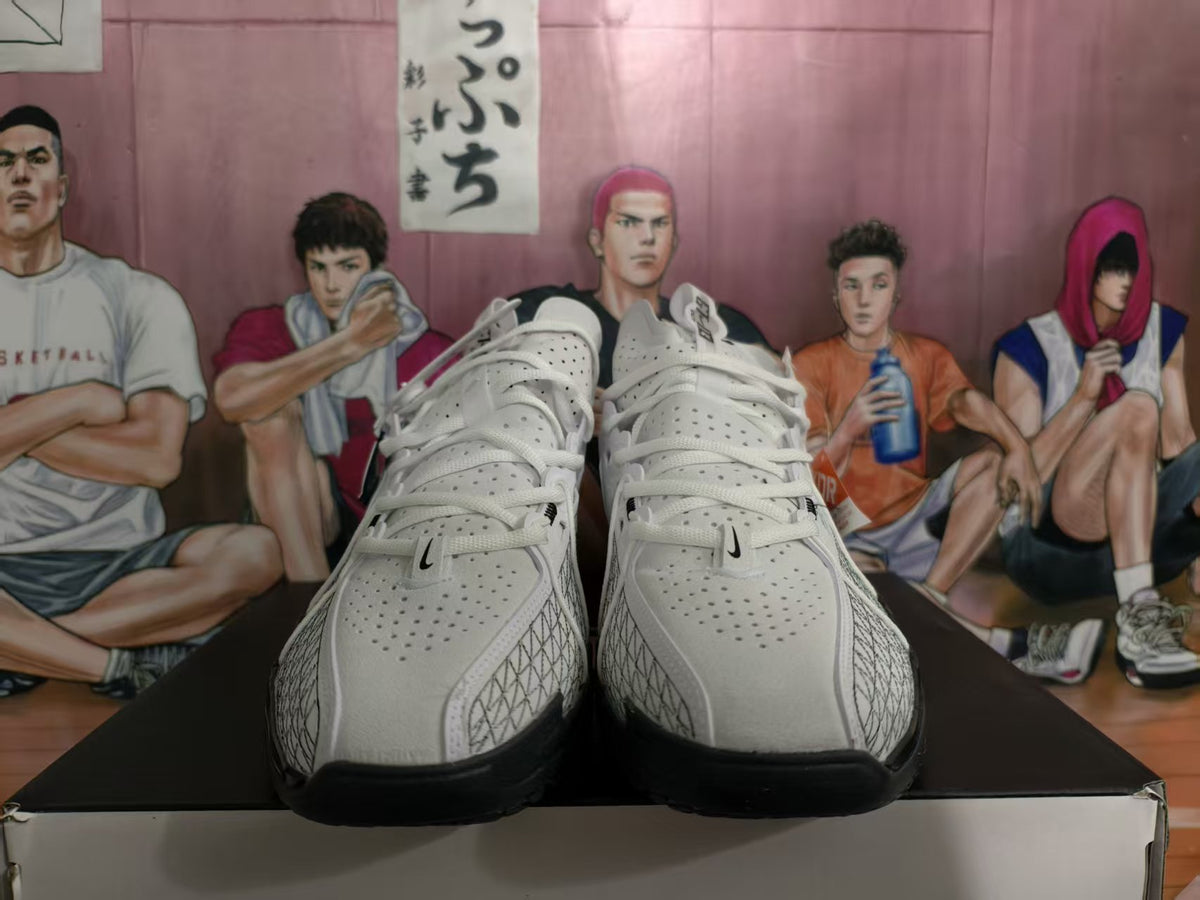 Front view of white Nike basketball sneakers with black outsole sections and perforated toe panels.