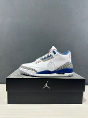 Side profile of a white Air Jordan 3 sneaker with blue accents and grey elephant-print detailing on a black shoebox.