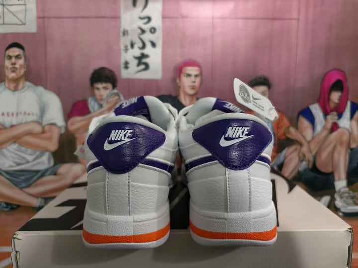 Rear view of white Nike sneakers with purple-blue heel panels and orange outsole accents, displayed on a shoebox.