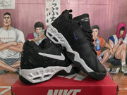 Angled view of black Nike sneakers showing contrasting white midsoles, black outsoles, and side branding.