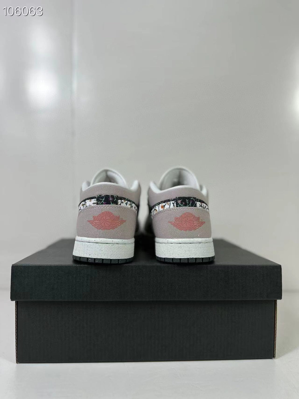 Rear view of the pink and sail low-top sneakers displayed on a black shoe box.