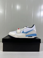 Single side profile showing the white low-top sneaker with blue accents, red strap detail and navy outsole.