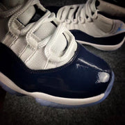 Close-up of the white laces, mesh tongue, stitching, and glossy navy toe overlay.