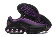 Black and purple Nike Air Max DN sneakers shown with the textured outsole visible