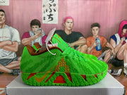 Side profile of a green Nike basketball sneaker showing the gold Swoosh-style detail, brown trim, and layered patterned outsole.