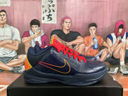 Side profile of a dark blue low-top basketball sneaker with red laces, gold and red side swoosh accents, and an orange heel panel.