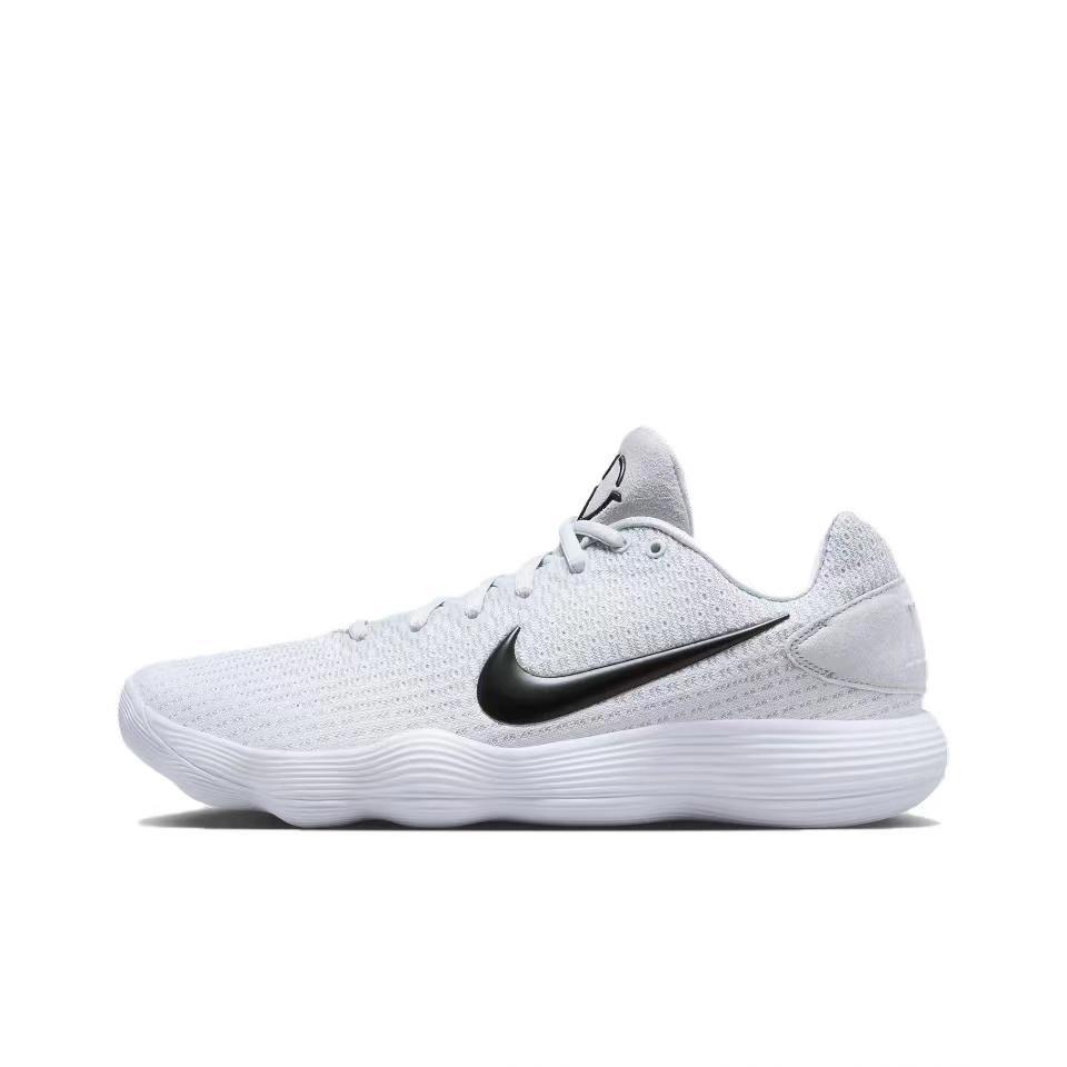 Side view of a white Nike low-top basketball sneaker with a black Swoosh and sculpted white outsole.