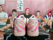 Rear view showing pink patterned heel panels and gold embroidered text on the white Nike sneakers.