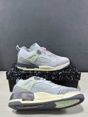 Angled side and outsole view of the grey and white Jordan Spizike Low sneakers, highlighting the ventilation panel, pale green lace support, and patterned tread.