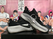 Angled view of a pair of black Nike sneakers with silver-gray side panels and sculpted soles.