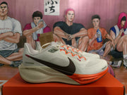 Side view showing the black Nike Swoosh, light-colored upper, orange forefoot outsole, and Air Zoom branding.