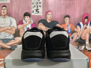 Rear view of black basketball sneakers with white heel panels and dark translucent-looking outsoles.