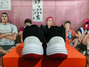 Rear view of the paired sneakers showing black collars, layered white heel panels, and red outsoles.