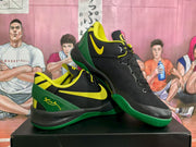 Angled view of the black and green basketball sneakers showing the yellow Swoosh, lace-up front, and textured green outsole.