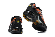 Rear and outsole views of black, white, and orange Nike Air Max Plus sneakers