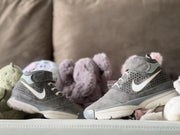 Side view of two gray high-top sneakers showing the patterned panels, contrasting side marks and layered soles.