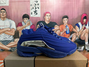 Side view of a blue sneaker showing sculpted panels and a silver-tone accent.
