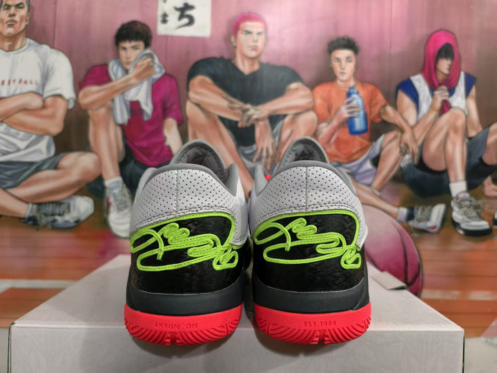 Rear view of the sneakers showing black heel panels, bright green detailing, red outsole sections and a basketball-themed background.