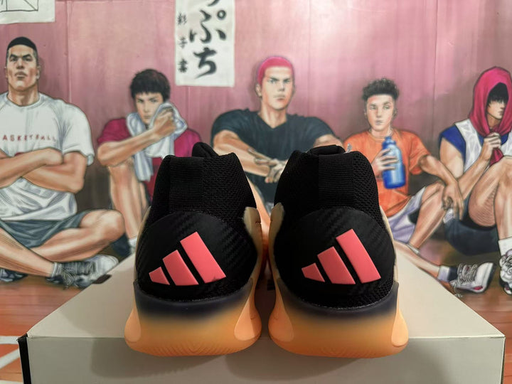 Rear view of black basketball shoes with orange soles and coral-pink three-stripe heel details
