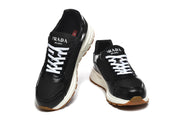 Front-facing view of black sneakers with white laces and branded tongues.