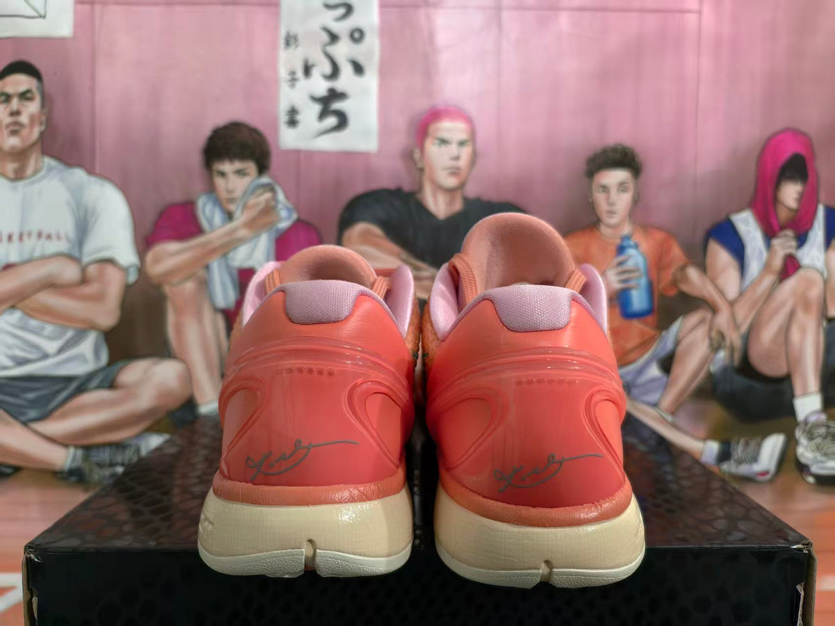 Rear view of coral-orange Nike Kobe basketball shoes with pink collars and light-colored soles.
