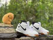 Pair of white and black high-top sneakers photographed outdoors, with Kobe-inspired graphics visible near the collars.