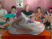 Side view of a white Nike basketball shoe with pink and purple accents and a black Swoosh