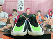 Front view of black lace-up basketball shoes with bright volt panels, white overlays, and white soles.