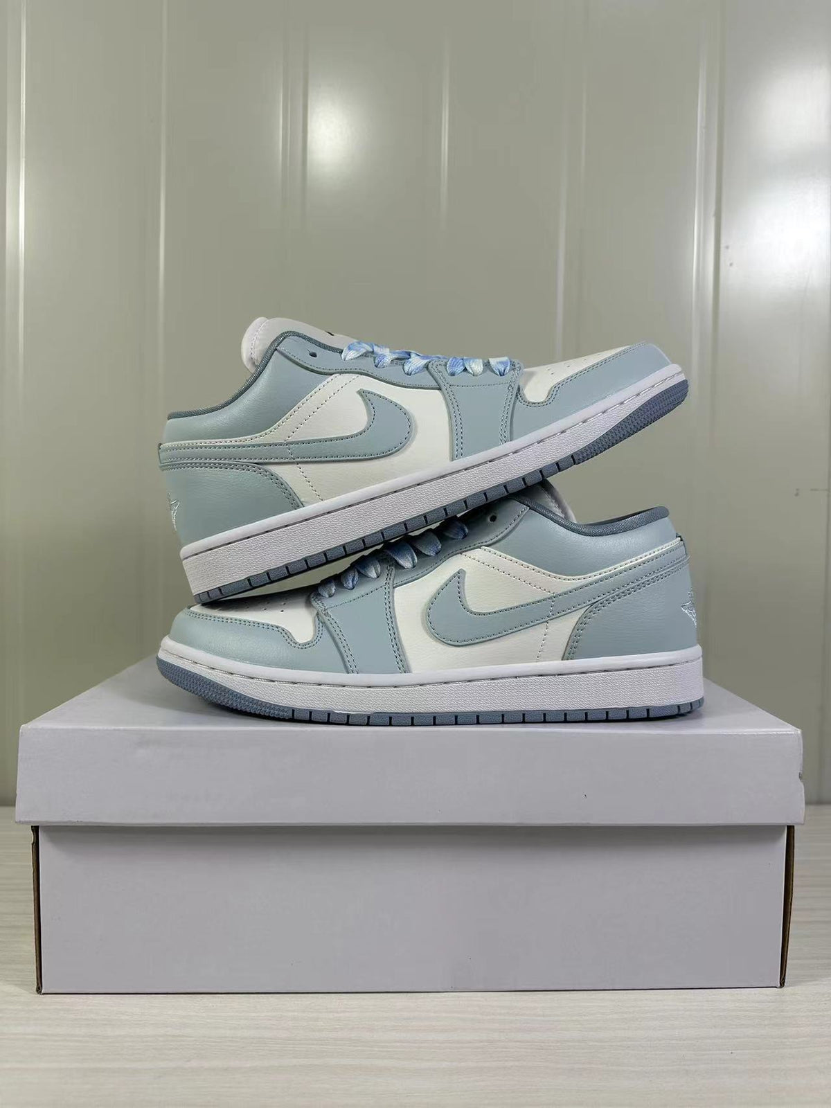 Pair of light blue-grey and white low-top sneakers displayed on a shoebox.