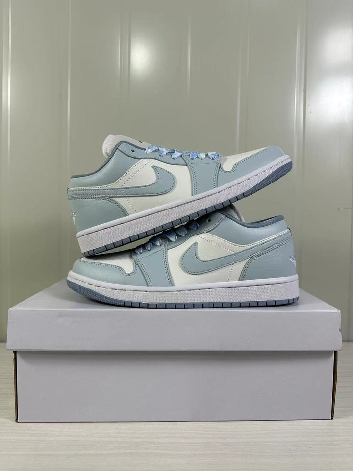Pair of light blue-grey and white low-top sneakers displayed on a shoebox.